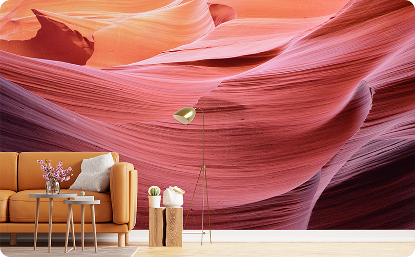 Pink canyon wallpaper mural with flowing coral and rose-colored rock layers behind a mustard yellow sofa